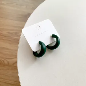 Detail view of vintage dark green wooden C-shaped stud earrings on jewelry card