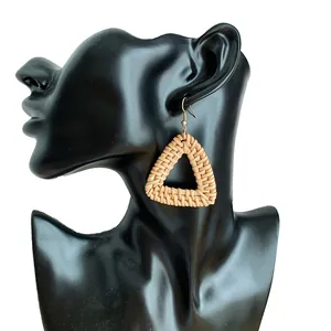 Detail of triangular woven straw earrings displayed on a black model head stand
