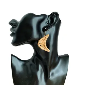 Detail view of handmade crescent woven earrings on model with golden metal hooks