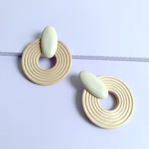 Detail of geometric round wooden earrings with concentric grooves on purple background