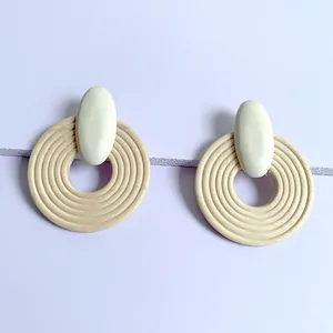 Close-up of geometric round wooden earrings with spiral texture on light purple background