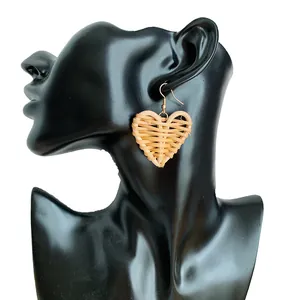 Macro detail of handmade heart-shaped rattan weave earrings on a model display