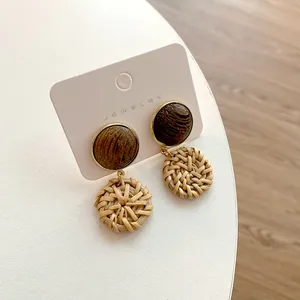 Macro shot of bohemian geometric round wooden and hand-woven rattan dangle earrings
