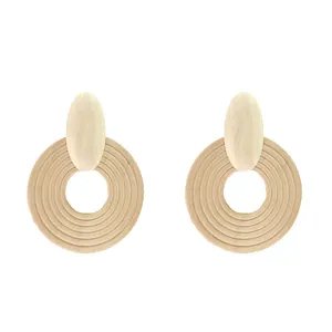 Detail of light beige wooden earrings featuring concentric geometric circles and natural grain