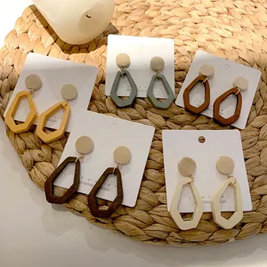 Set of five bohemian geometric wood dangle earrings in various earthy colors on straw mat