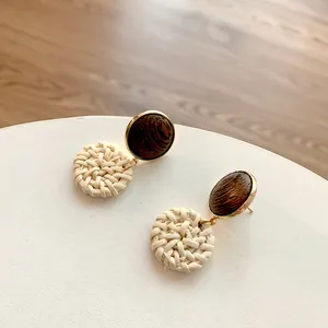 Detailed view of dark wood and woven rattan geometric earrings with golden metallic accents