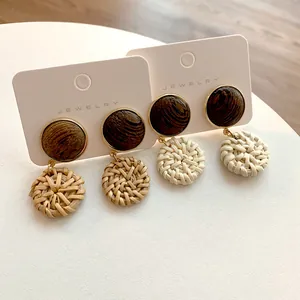 Detailed view of bohemian wood and rattan woven earrings with golden metal frames