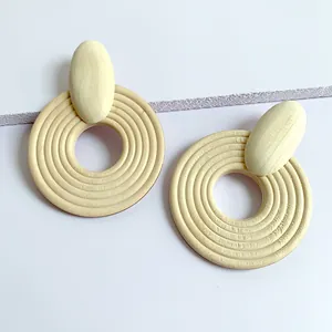 Macro detail of geometric wooden drop earrings featuring textured concentric circles