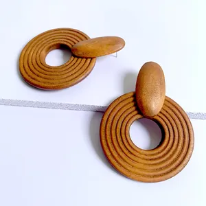 Macro view of geometric wooden hoop earrings with detailed spiral texture on white background