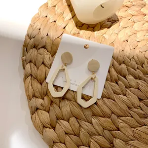 Retro geometric hollow pentagon drop earrings with beige wooden texture on display