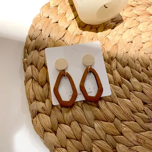 Retro geometric wooden drop earrings in dark brown and cream on a jewelry card