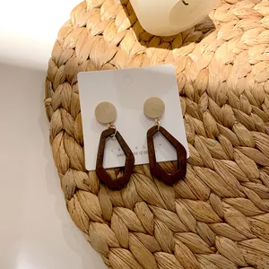Detail of geometric wooden earrings with round studs and dark brown hexagonal pendants