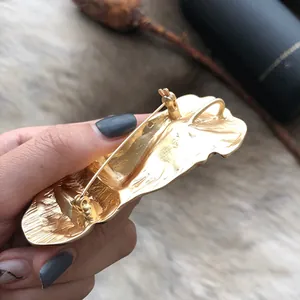 Back view of a gold matte human face brooch with a sturdy pin buckle mechanism