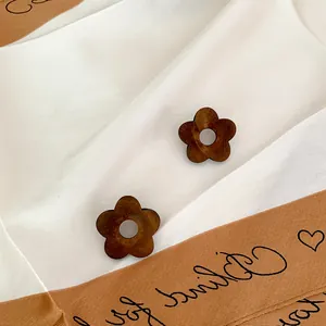 Minimalist wooden flower stud earrings in dark brown finish on elegant white silk fabric