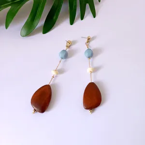 Detalle de pendientes largos con cuentas de resina azul y colgante de madera marrón