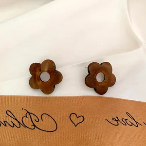 Minimalist wooden flower stud earrings in dark brown finish on elegant white satin