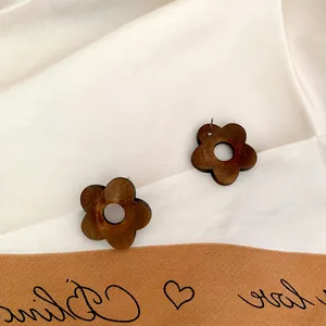 Deep brown wooden five-petal flower earrings on white silk background with prop card
