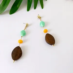 Detalle de pendientes largos con cuentas de resina y colgantes de madera de color café