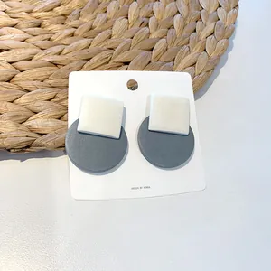 Detail view of geometric square and round stud earrings on a white display card