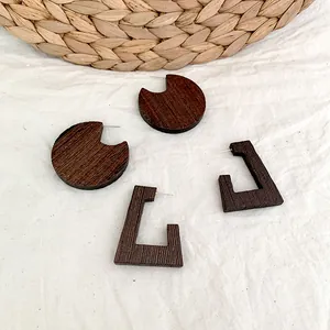 Retro geometric dark brown wooden earrings with natural texture on a linen fabric background