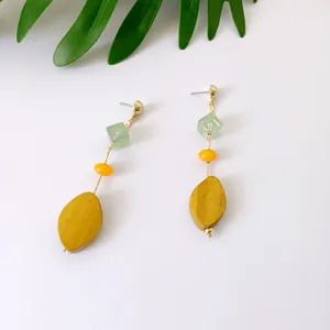 Detalle de aretes largos coloridos con cuentas de resina y colgantes de madera amarilla