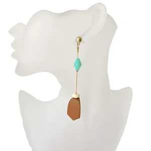 Primer plano de pendientes largos con cuentas verde menta y colgantes de madera marrón