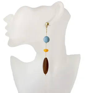 Detalle de pendientes largos con cuentas de resina azules, amarillas y marrones en cadena