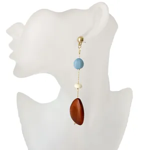 Vista detallada de pendientes largos con borlas y cuentas de madera azules, crema y café