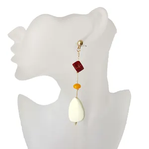 Detalle de pendientes largos de resina geométrica con cuentas de colores en un maniquí