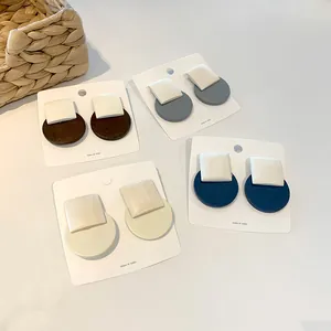 Detailed close-up of minimalist geometric round and square wooden stud earrings in four colors