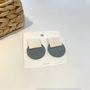 Detail of Korean-style geometric earrings with matte cream square and grey-blue circle
