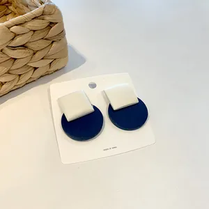Detail of minimalist geometric earrings with white square and navy round elements