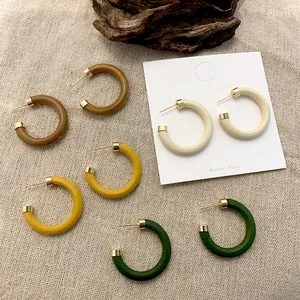 Macro detail of vintage wood resin C-shaped hoop earrings with silver posts and gold accents
