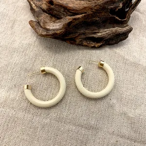 Minimalist cream wooden C-shaped hoop earrings with gold accents on rustic linen background