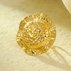 Primo piano di un anello dorato irregolare con texture martellata su sfondo in pietra