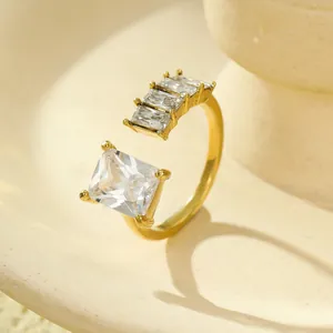 Vista macro di un anello dorato aperto con zirconi a taglio quadrato e baguette