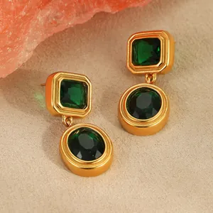 Macro detail of emerald zircon earrings with square and oval gems on 18K gold plated base