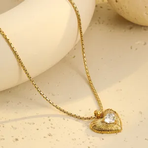 Collar de acero inoxidable dorado con colgante de corazón y circón sobre base de piedra