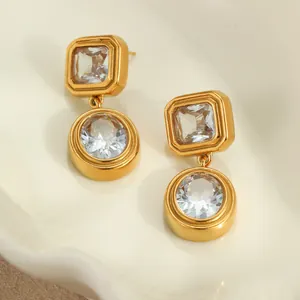 Vintage geometric gold earrings with clear zircon stones on a ceramic tray