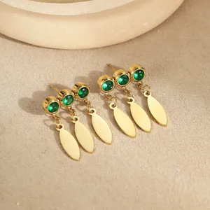 Close-up of 18K gold-plated earrings with emerald green zircons and leaf pendants