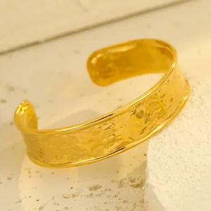 Dettaglio del bracciale aperto dorato con texture martellata su base minerale