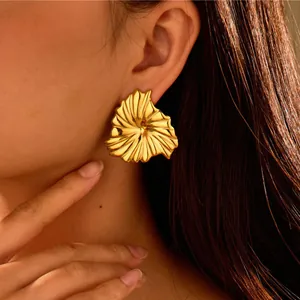 Primer plano de pendientes de titanio chapados en oro con textura radial en una modelo