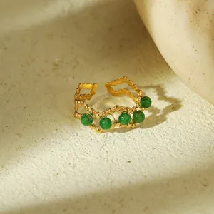 Detail van de verstelbare gouden ring met golftexturen en vijf groene natuurstenen