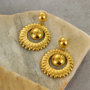 Primer plano de pendientes vintage de sol bañados en oro de 18k sobre piedra natural