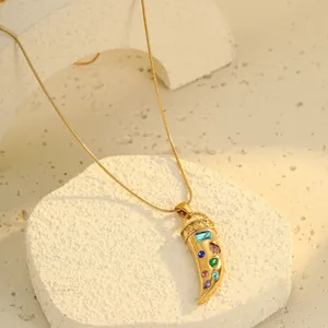 Gold horn pendant necklace with colorful zircons on white stone display base