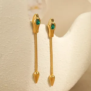 Detail of gold snake drop earrings with emerald green stones and long chain fringe