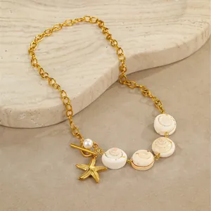 Gold ocean necklace with natural shell, starfish charms and toggle clasp on stone tray