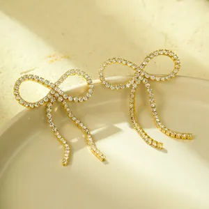 Nahaufnahme von goldenen Schleifenohrringen mit Zirkonia-Mikropavé auf Keramikschale