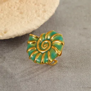 Detail of nautical conch shell ring with gold finish and green enamel accents