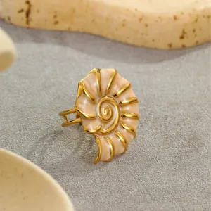Detailed macro view of cream enamel conch ring with gold ribs on stone pedestal